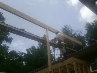 Carpenter setting a ridge beam over a new addition frame — Ice Dam Removal by Roofing Brothers in Roland