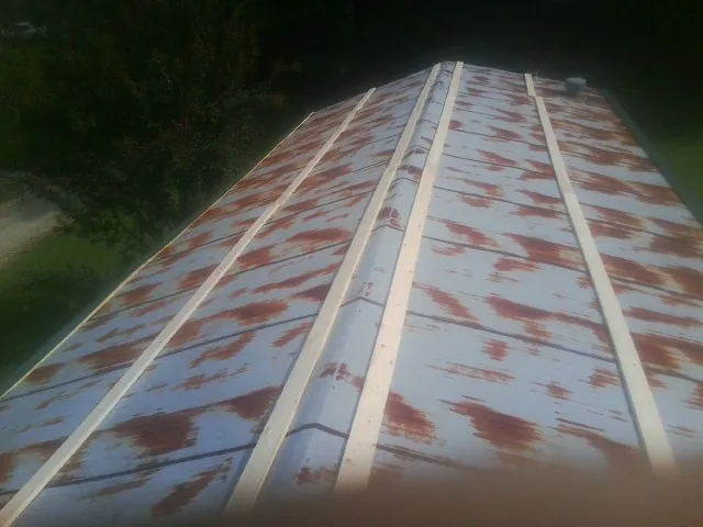 Rusted metal roof panels with new wood purlins before replacement — Storm Damage Roof Repair in Roland by Roofing Brothers