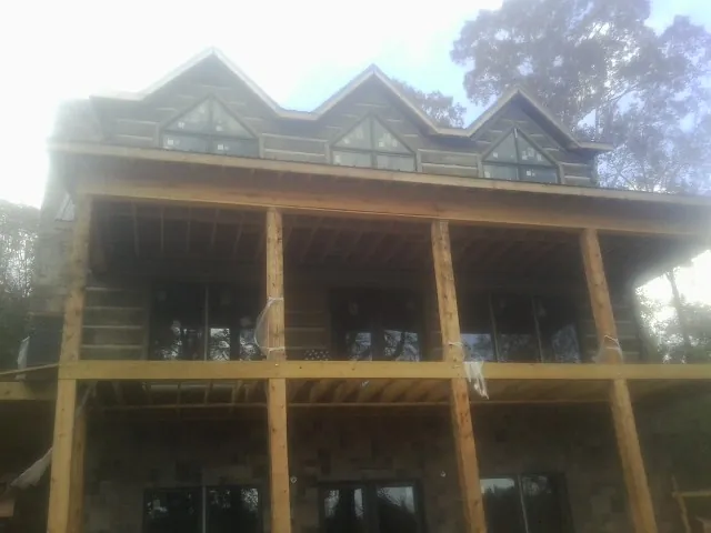 Dormers and porch framing on a large log home under construction — Roof Coating work by our crew in Roland