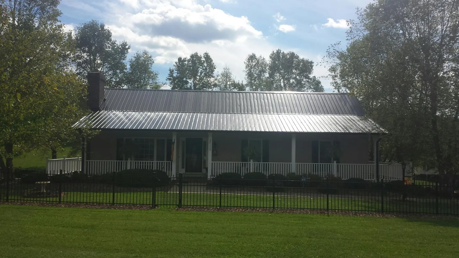 Gray metal roof on a brick ranch with a full width front porch — Gutter Guard Installation work by our crew in Roland