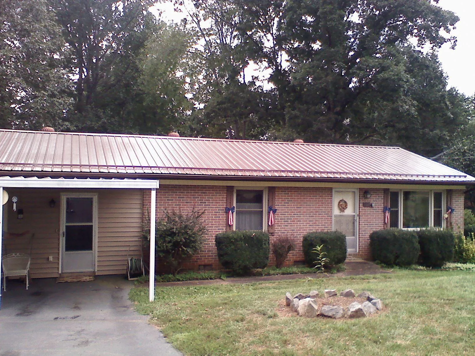 Bronze metal roof and carport on a brick ranch home — Roof Repair work by our crew in Roland