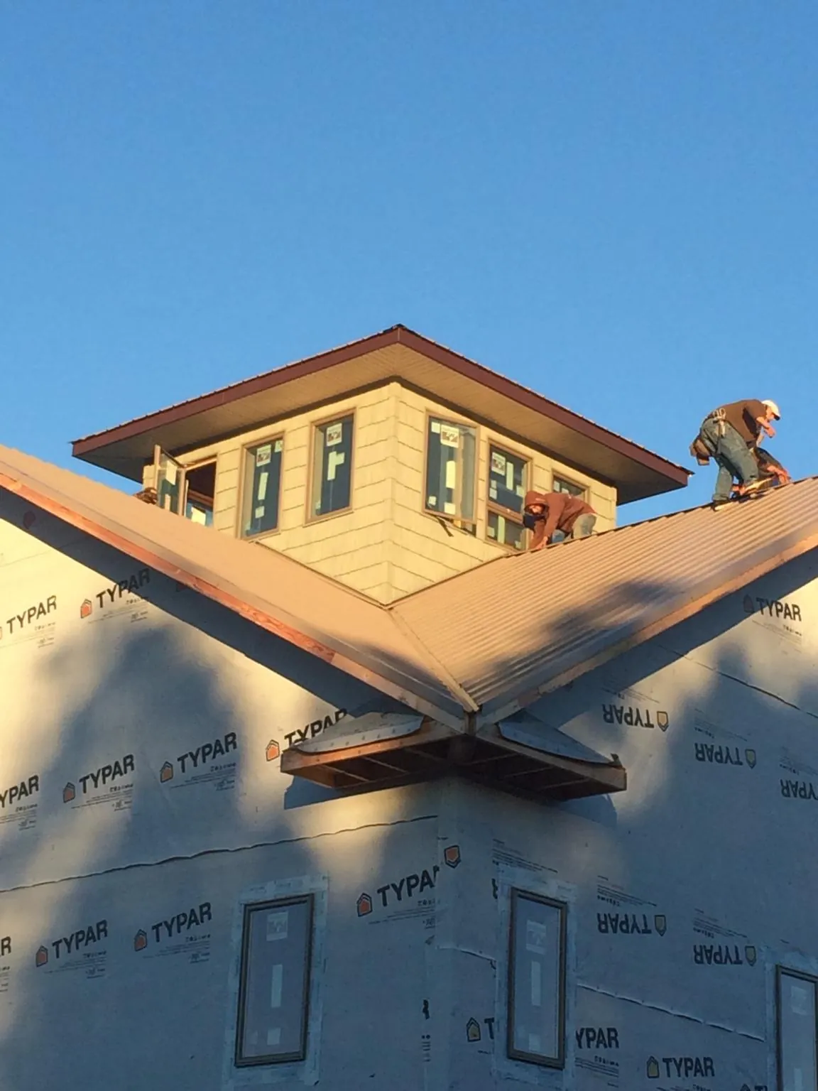 Roofers working around a rooftop cupola on a new metal roof at sunset — Roof Waterproofing in Roland by Roofing Brothers